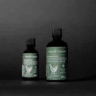 Hendl Garum Zwei Flaschen Hendl Garum Hühnerwürzsauce vor dunklem Hintergrund